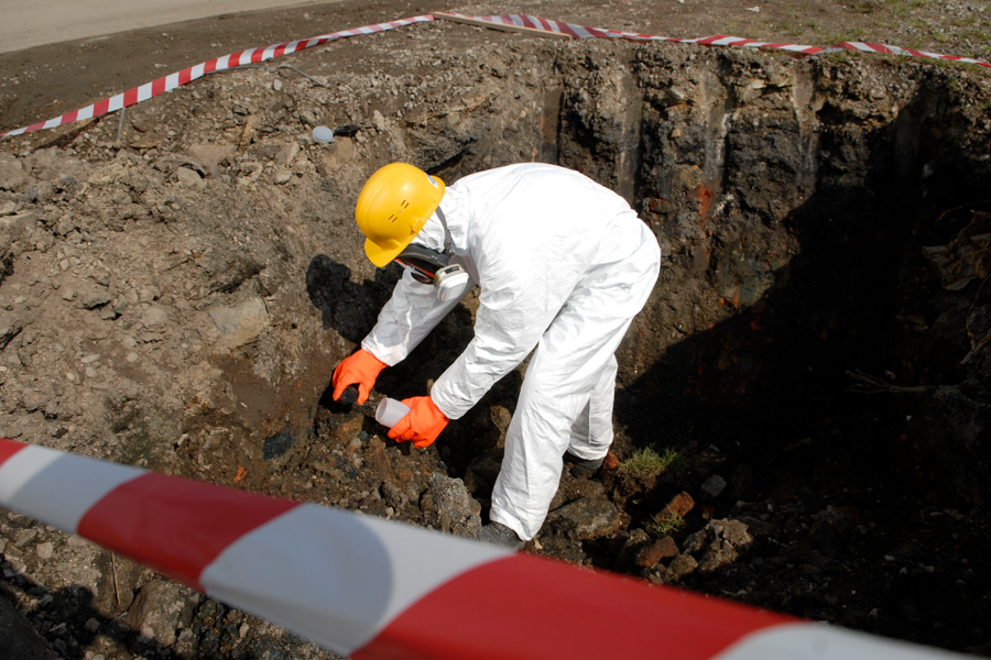 man in helmet collecting samples from soil